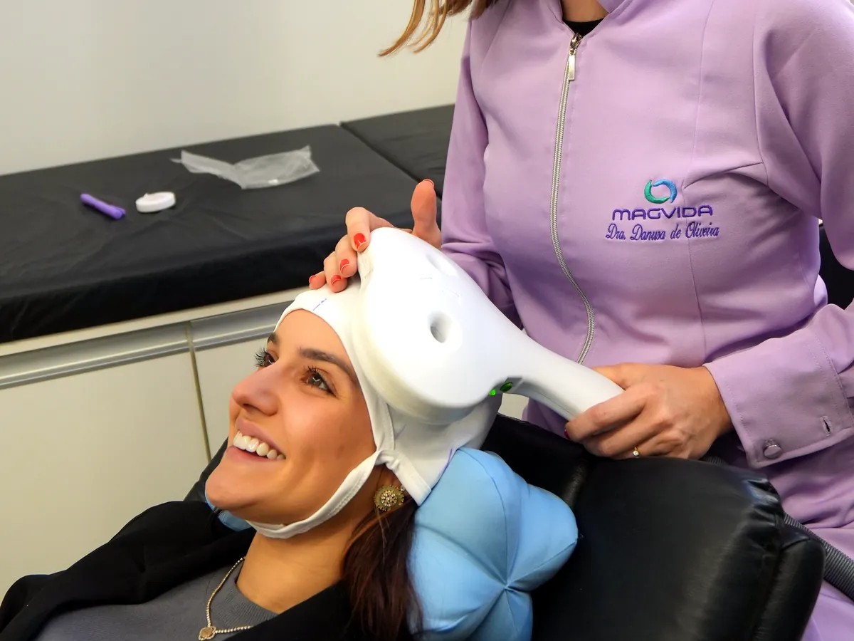 Paciente sorrindo enquanto a fisioterapeuta posiciona a bobina de estimulação magnética