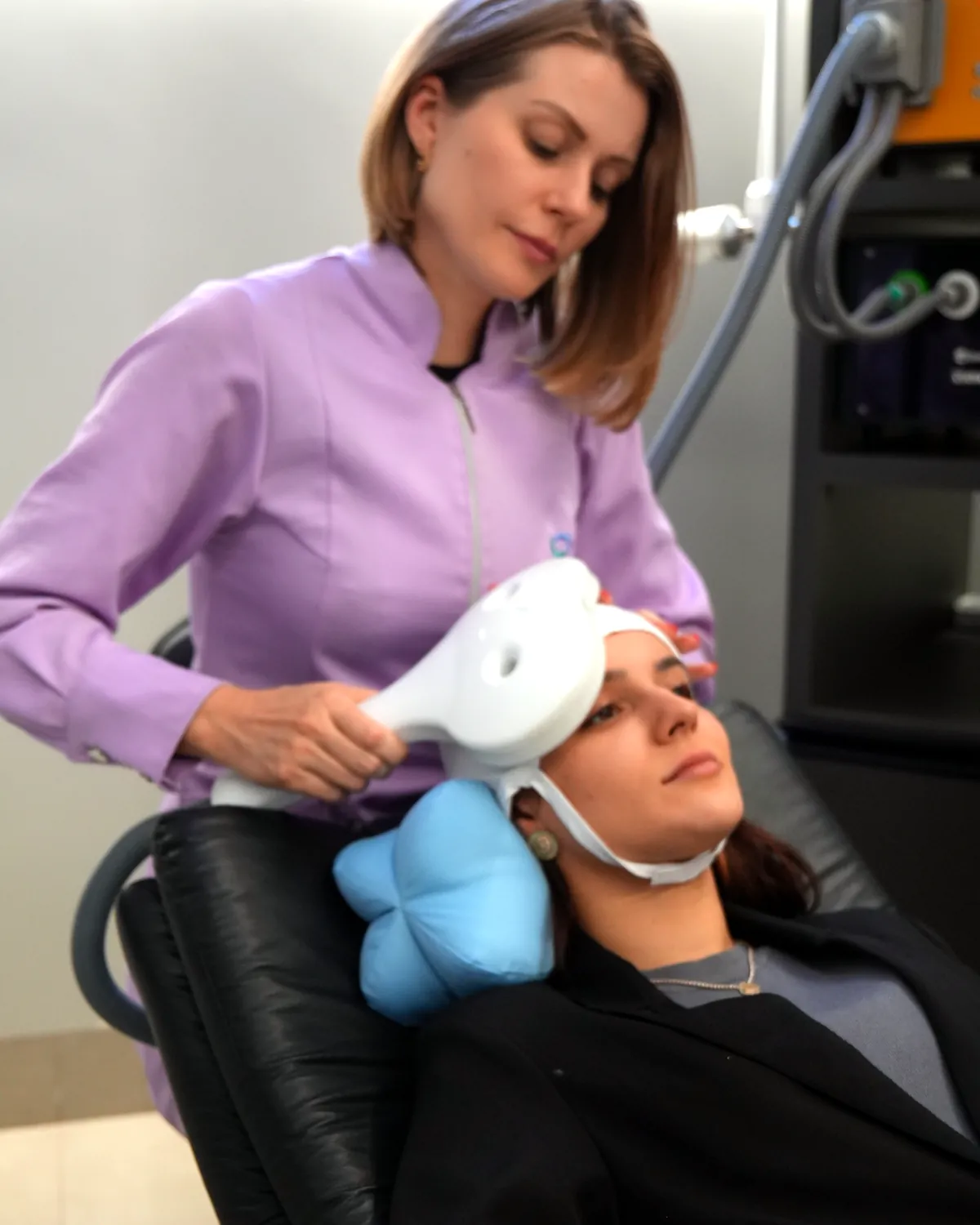 Fisioterapeuta posicionando a bobina de estimulação magnética na cabeça da paciente